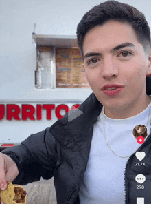 a young man eating a burrito in front of a burrito restaurant