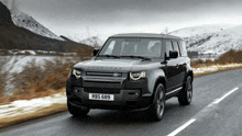 a black land rover defender driving down a road