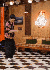 a man is dancing in a room with a couch and a neon sign that says good morning