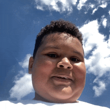 a boy with a blue sky and white clouds in the background