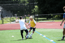 two boys are playing soccer on a field and one is wearing a yellow jersey