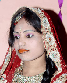 a woman wearing a red and gold dress has a nose ring on her nose