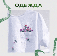 a white shirt with embroidered flowers in a pocket and the word одежда above it