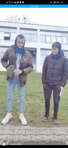 two boys standing next to each other in front of a building with a snap sent message on the screen