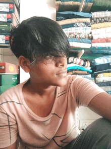 a young boy sitting in front of a shelf with shirts on it and a box that says 40