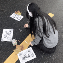 a girl wearing headphones sits on the ground drawing on a piece of paper