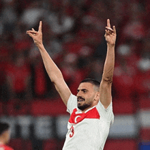 a soccer player with the number 3 on his jersey is raising his arms in the air