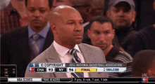 a man in a suit and tie stands in front of a scoreboard that says copyright 2014 national basketball association