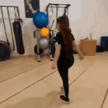 a woman is standing on a mat in a gym with a bunch of exercise balls .