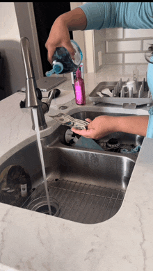 a woman is washing dishes in a kitchen sink while pouring soap into a bottle