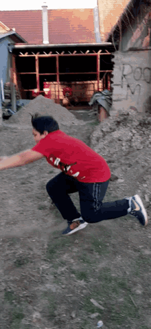 a boy in a red shirt is jumping in the air in front of a building with the word rod written on it