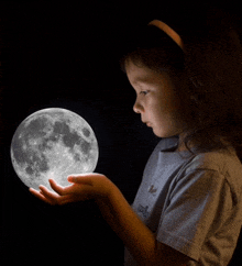 a girl in a gray shirt holds a full moon in her hands