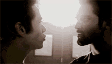 two men are standing next to each other and looking at each other in a dark room .