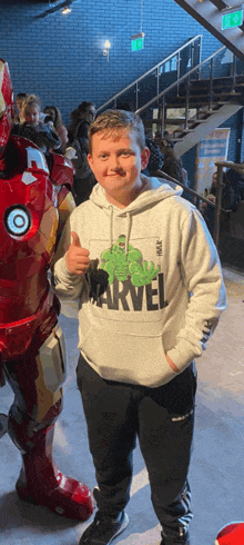 a boy wearing a hoodie that says marvel is giving a thumbs up