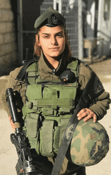 a female soldier holds a helmet and a gun