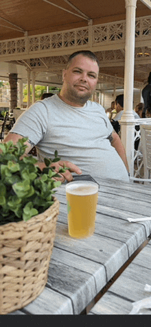 a man sits at a table with a cup of beer on it