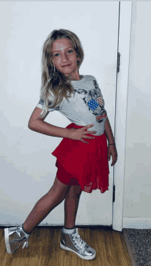 a young girl wearing a red skirt and a gray shirt