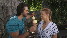 a man and a woman are standing next to each other and the man is holding a cone of ice cream