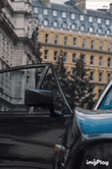 a black and blue car is parked in front of a building .