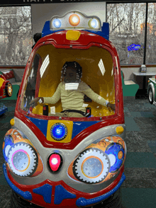 a little girl sits in a colorful toy car with lights on