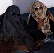 two people sitting on a couch with their faces covered by scarves