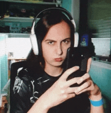 a girl wearing headphones is taking a selfie with her phone .