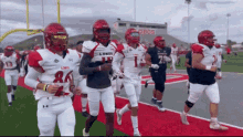 a group of football players are running on a field with a stadium in the background that has the word lobos on it