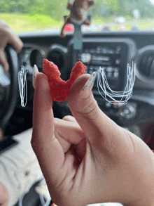 a person holding a red candy in their hand