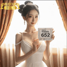 a woman in a white dress holds a sign that says ' togel 652 '