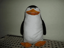 a stuffed penguin is standing on a table .