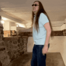 a man with long hair and sunglasses is standing in a room