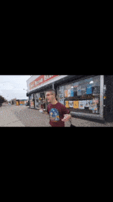 a man walking down a sidewalk in front of a store that says ' short island beach ' on it