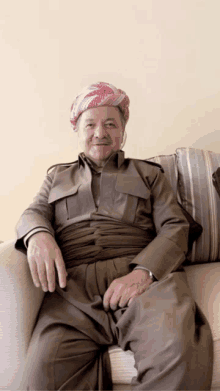 a man wearing a turban sits on a couch and smiles