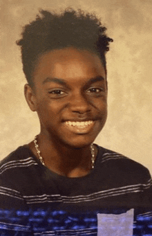 a young man is smiling for the camera while wearing a striped shirt .