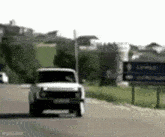 a white truck is driving down a road in front of a sign that says ' minas ' on it .