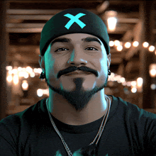 a man with a beard is wearing a beanie with a blue x on it