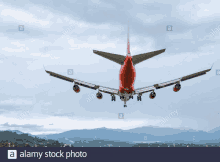 a red airplane is flying in the sky over mountains