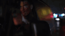 a man is pointing a gun at the camera while sitting in a car .