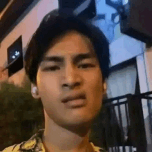 a young man wearing ear buds is making a funny face while standing in front of a building .