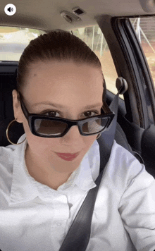 a woman in a car wearing sunglasses and a nose ring