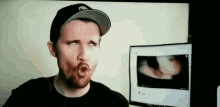 a man making a funny face in front of a computer screen