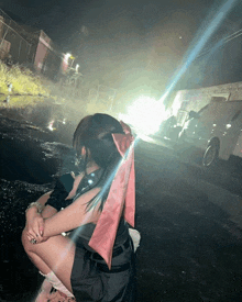 a woman with a pink bow in her hair is kneeling down in front of a car