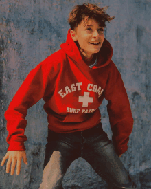 a young boy wearing a red east coast surf patrol sweatshirt