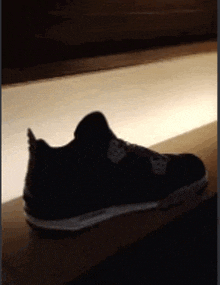 a black shoe is sitting on top of a wooden shelf