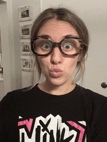 a woman wearing glasses and a shirt that says nmd makes a funny face