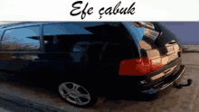 a black car is parked in front of a sign that says efe çabuk