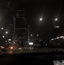 a car is driving down a highway at night in front of a cnn media building