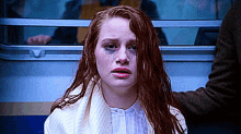 a woman with red hair and a black eye is sitting on a bus with a man .