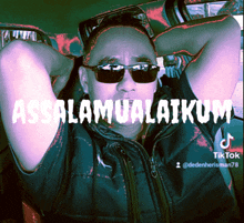 a man wearing sunglasses has his hands behind his head and the words assalamualaikum are above him