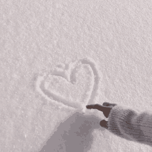 a person drawing a heart in the snow